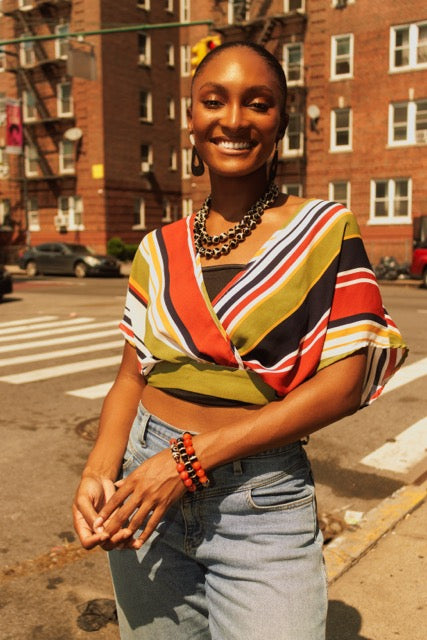 Woman wearing a colorful striped top and jeans on a city street.
