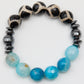 Bracelet with black and white patterned beads and blue faceted beads on a white background