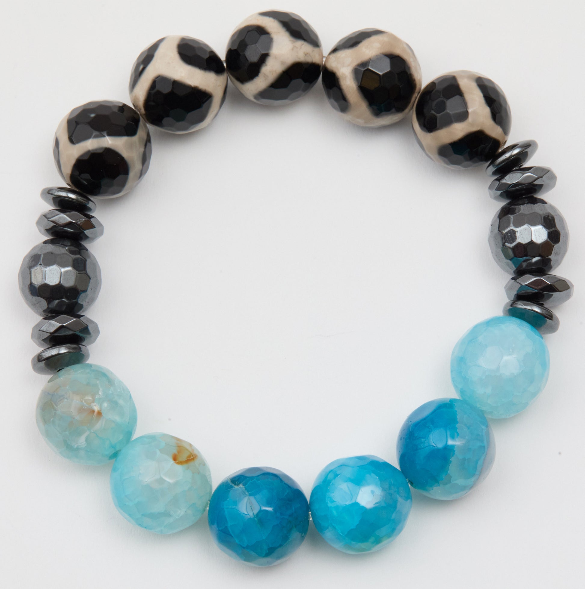 Bracelet with black and white patterned beads and blue faceted beads on a white background