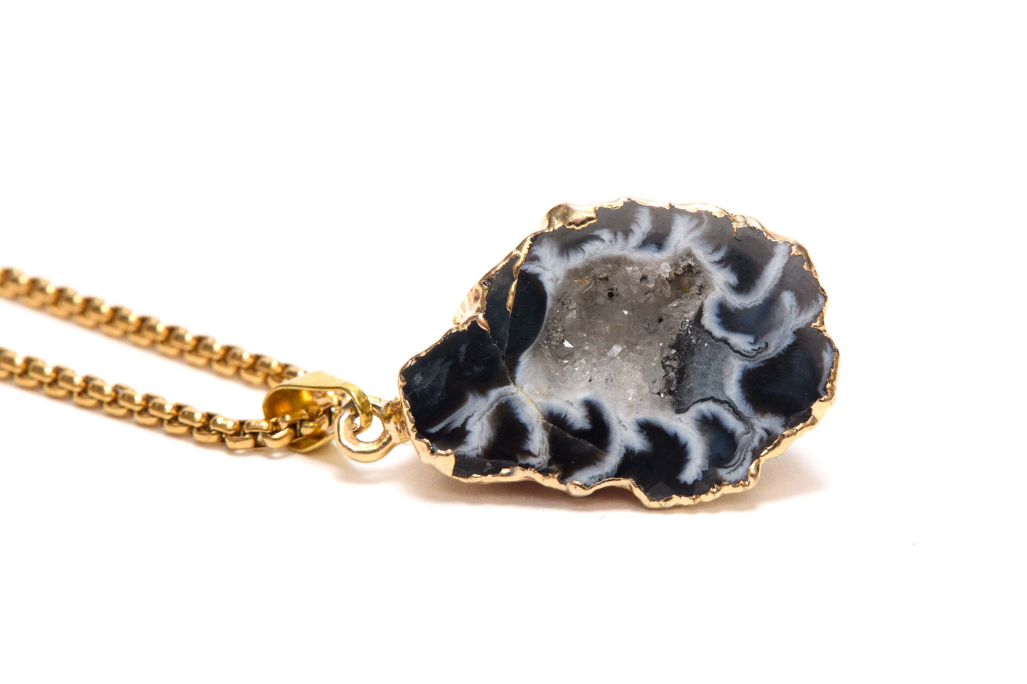 Necklace with a black and white agate pendant on a gold chain against a white background