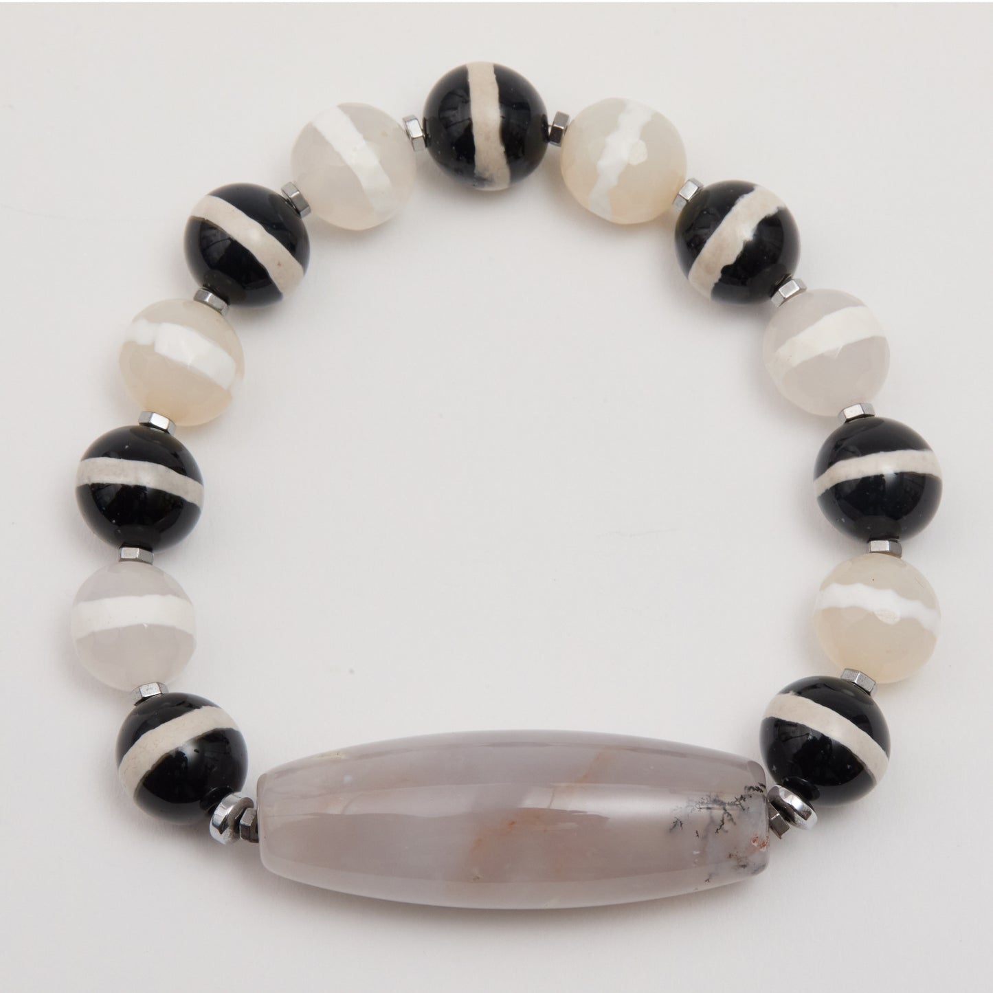 Bracelet with black, white, and brown beads on a light gray background