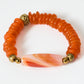 Orange beaded bracelet with gold accents and a orange banded stone on a white background