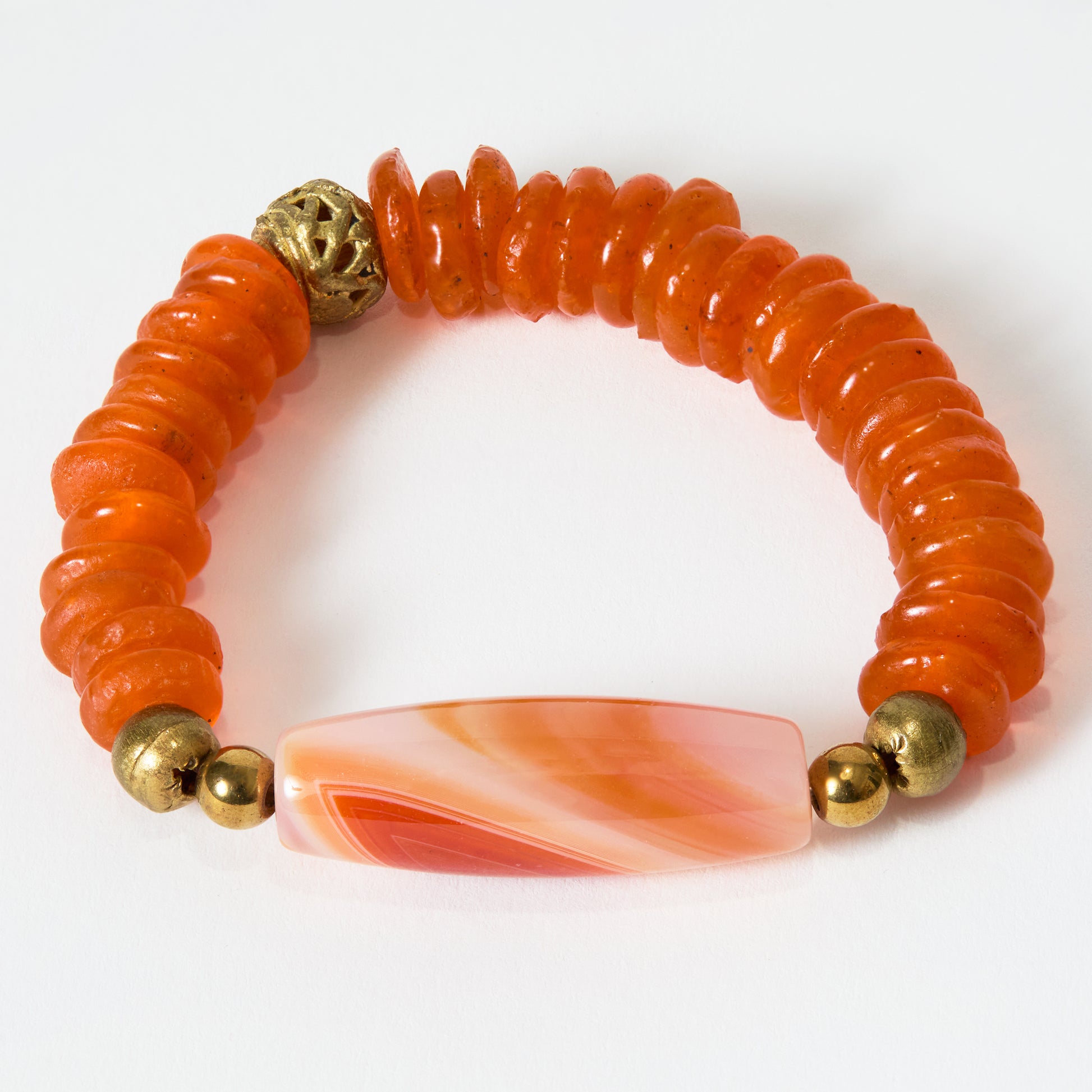 Orange beaded bracelet with gold accents and a orange banded stone on a white background