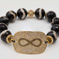 Bracelet with black and white beads and a gold infinity symbol focal on a white background