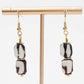Pair of earrings with black and white beads on a gold earring stand against a white background