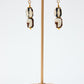 Pair of earrings on a gold stand with a white background