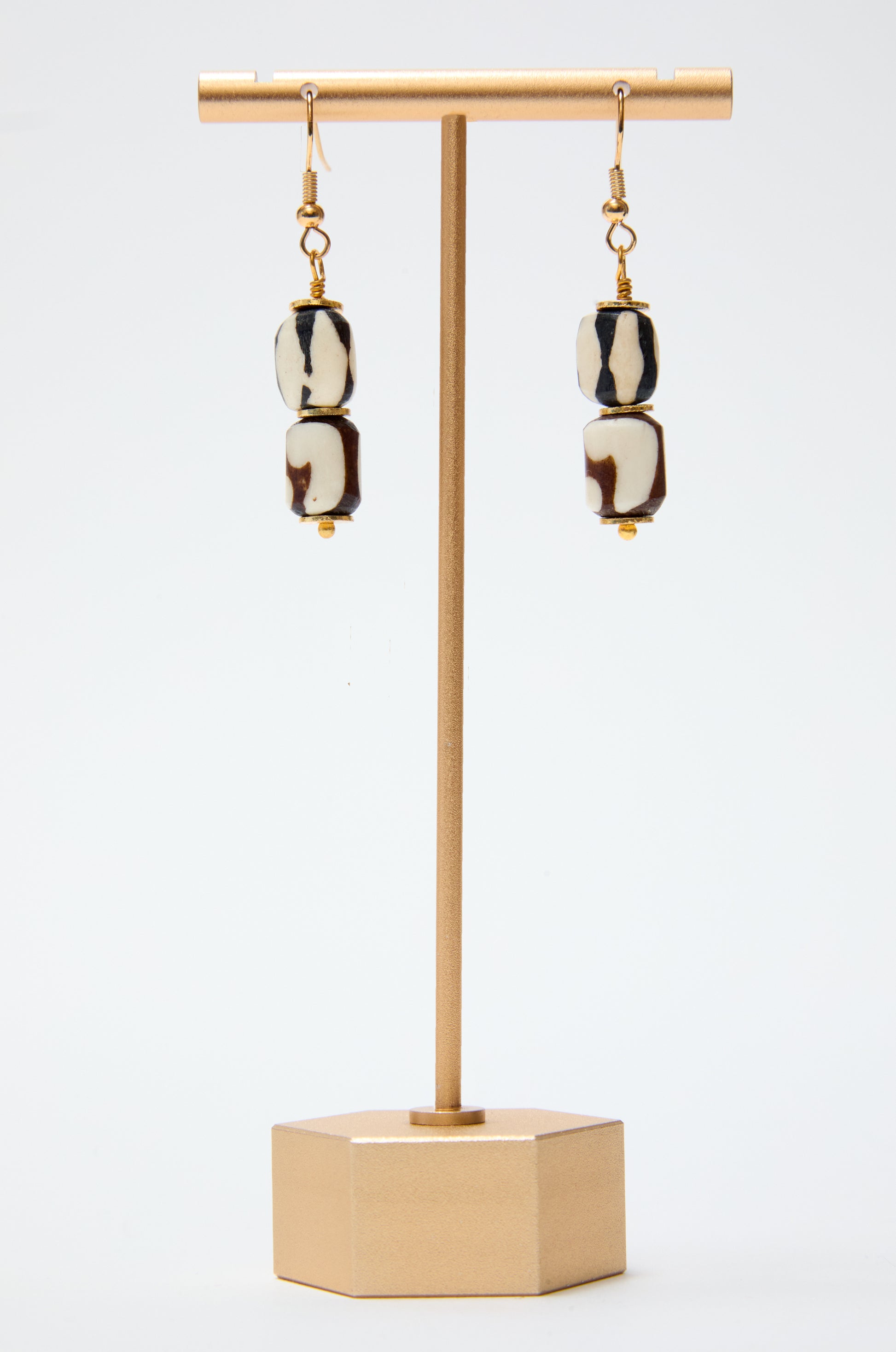 Pair of earrings on a gold stand with a white background