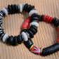 Beaded bracelet with black, red, and white beads on a textured surface
