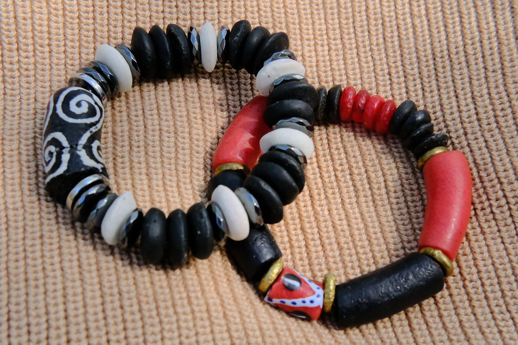 Beaded bracelet with black, red, and white beads on a textured surface