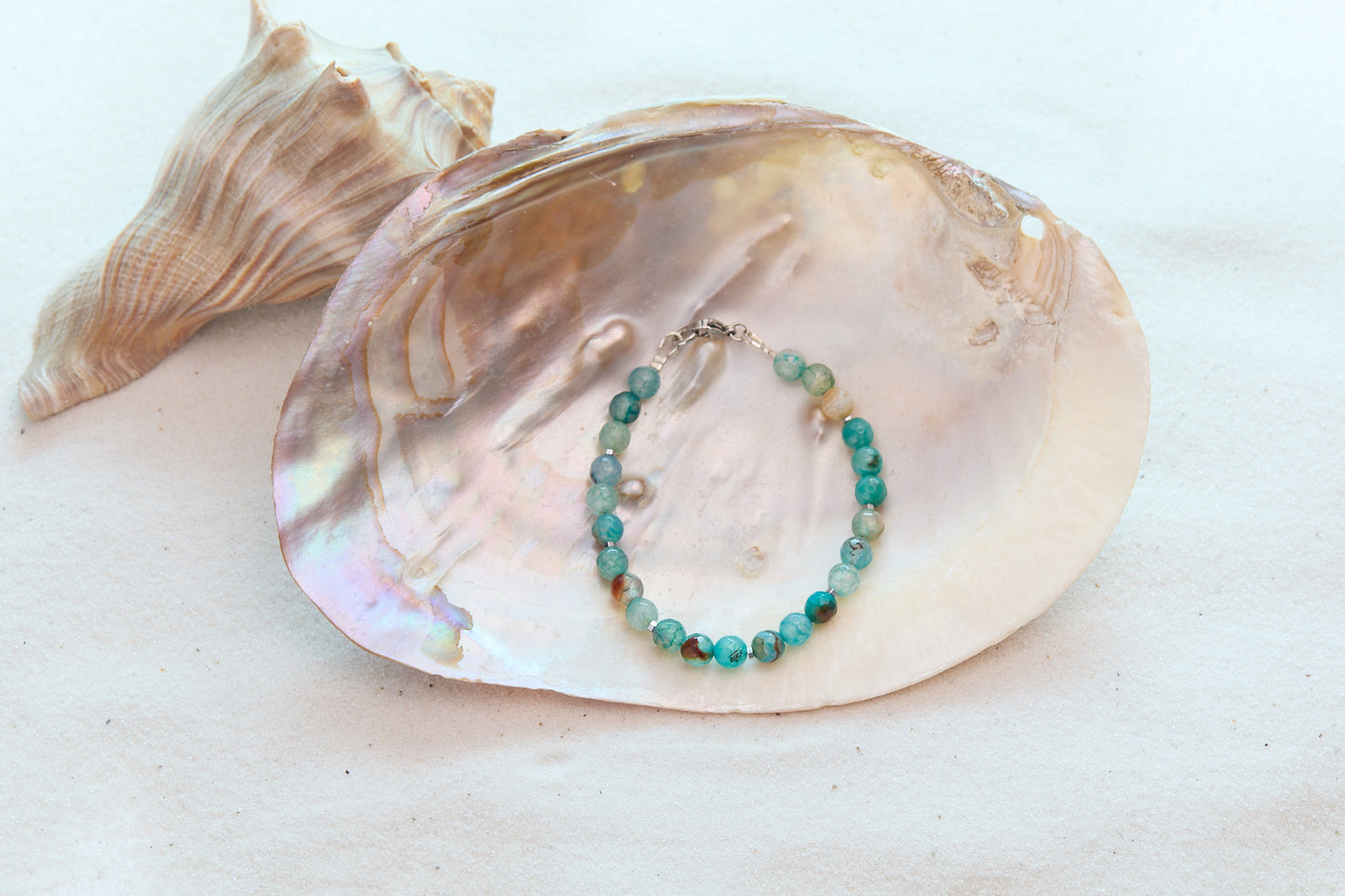 Beaded bracelet on a large shell with a white background