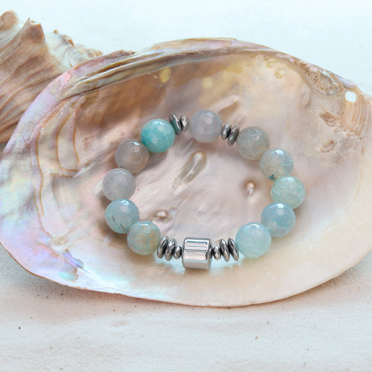Bracelet with light blue beads and silver accents on a seashell background