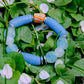 Blue beaded bracelet on green leaves with flowers