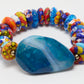 Colorful beaded bracelet with a large blue stone on a white background