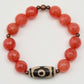 Bracelet with red beads and a decorative brown and white bead on a white background
