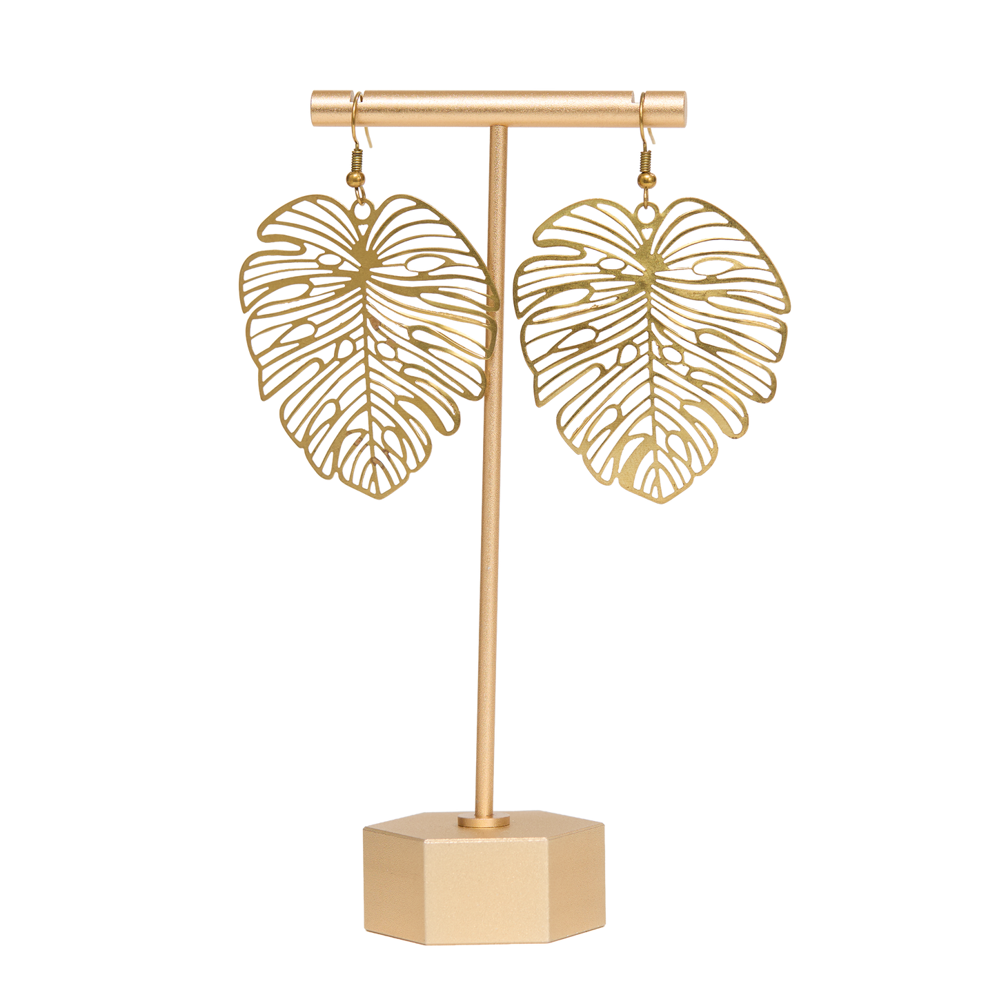 Brass monstera leaf-shaped earrings on a matching stand with a white background