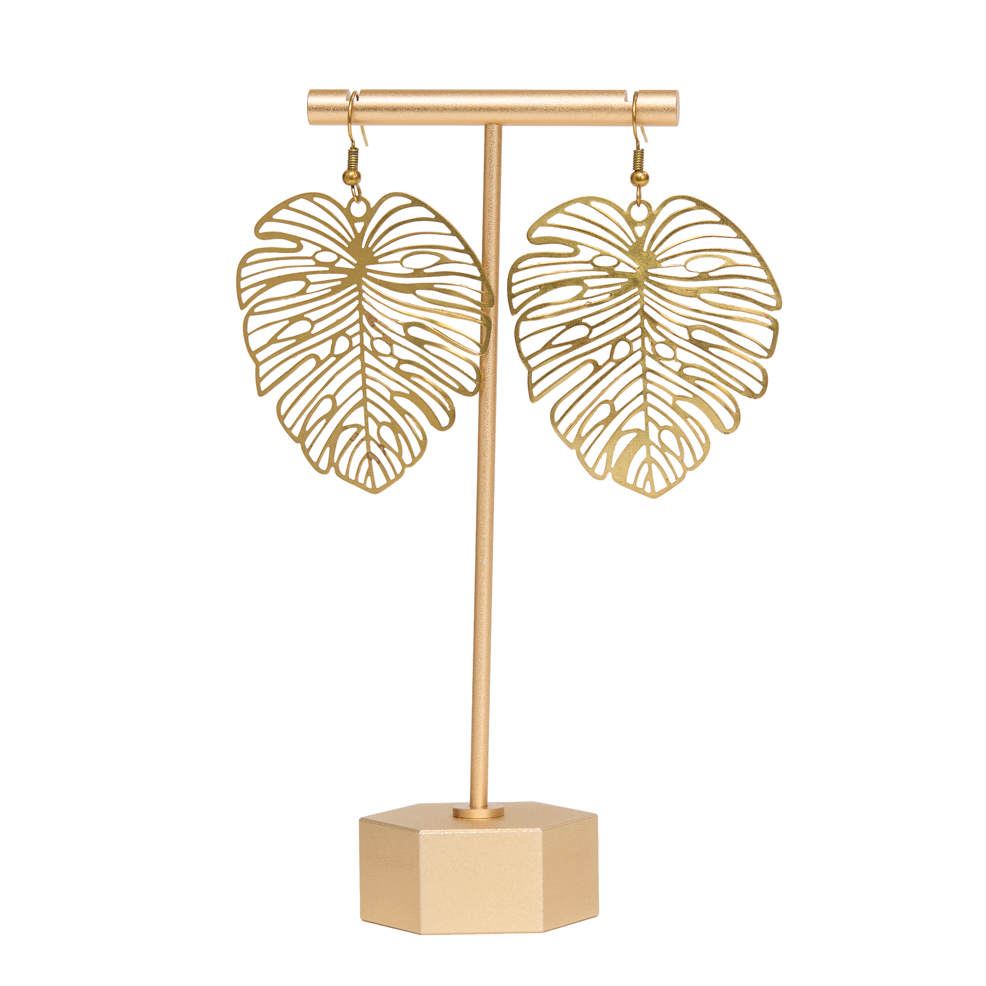 Brass monstera leaf-shaped earrings on a matching stand with a white background