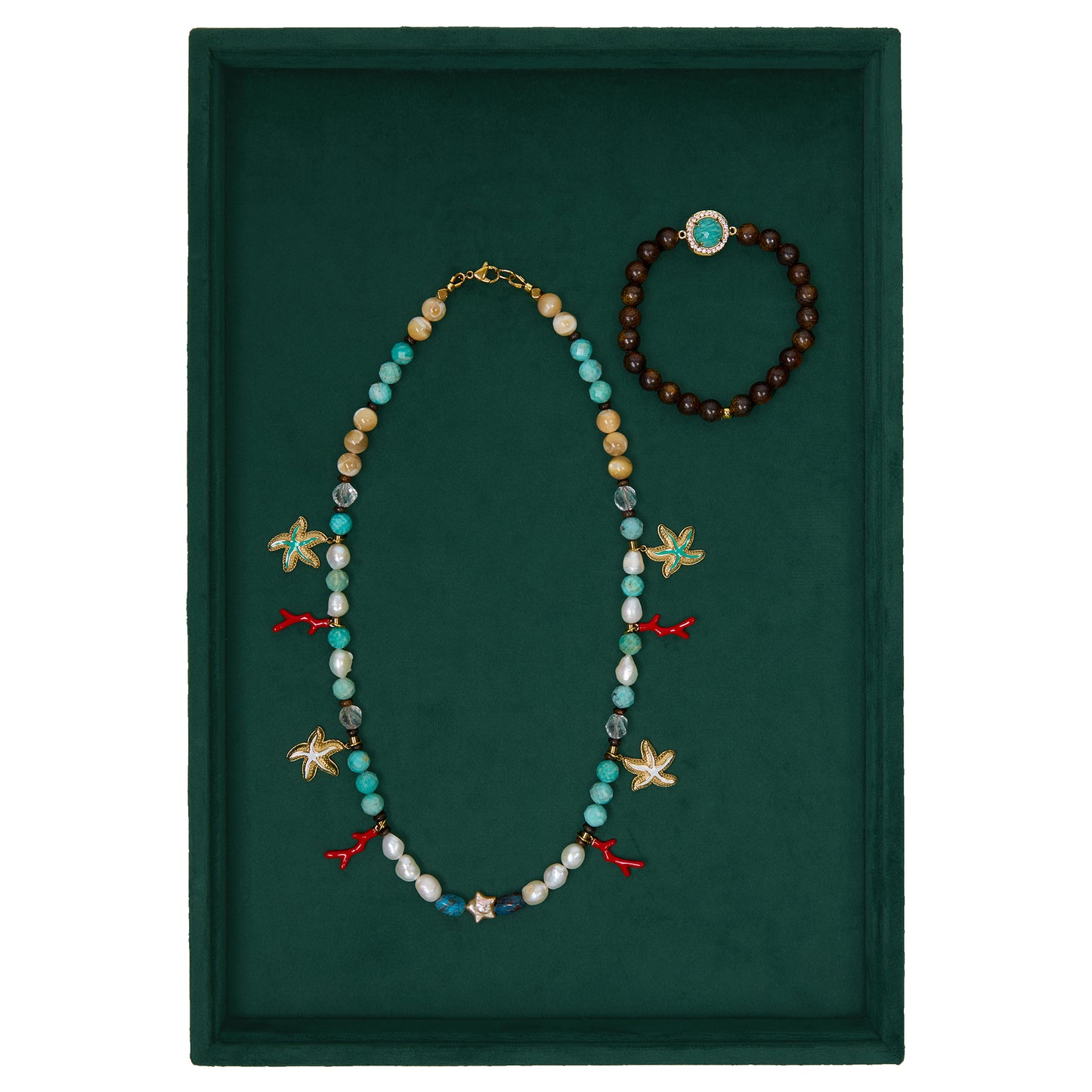 Necklace with starfish and fish charms and a bracelet on a green background