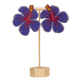 Hand-painted purple hibiscus flower earrings on a gold stand on a white background