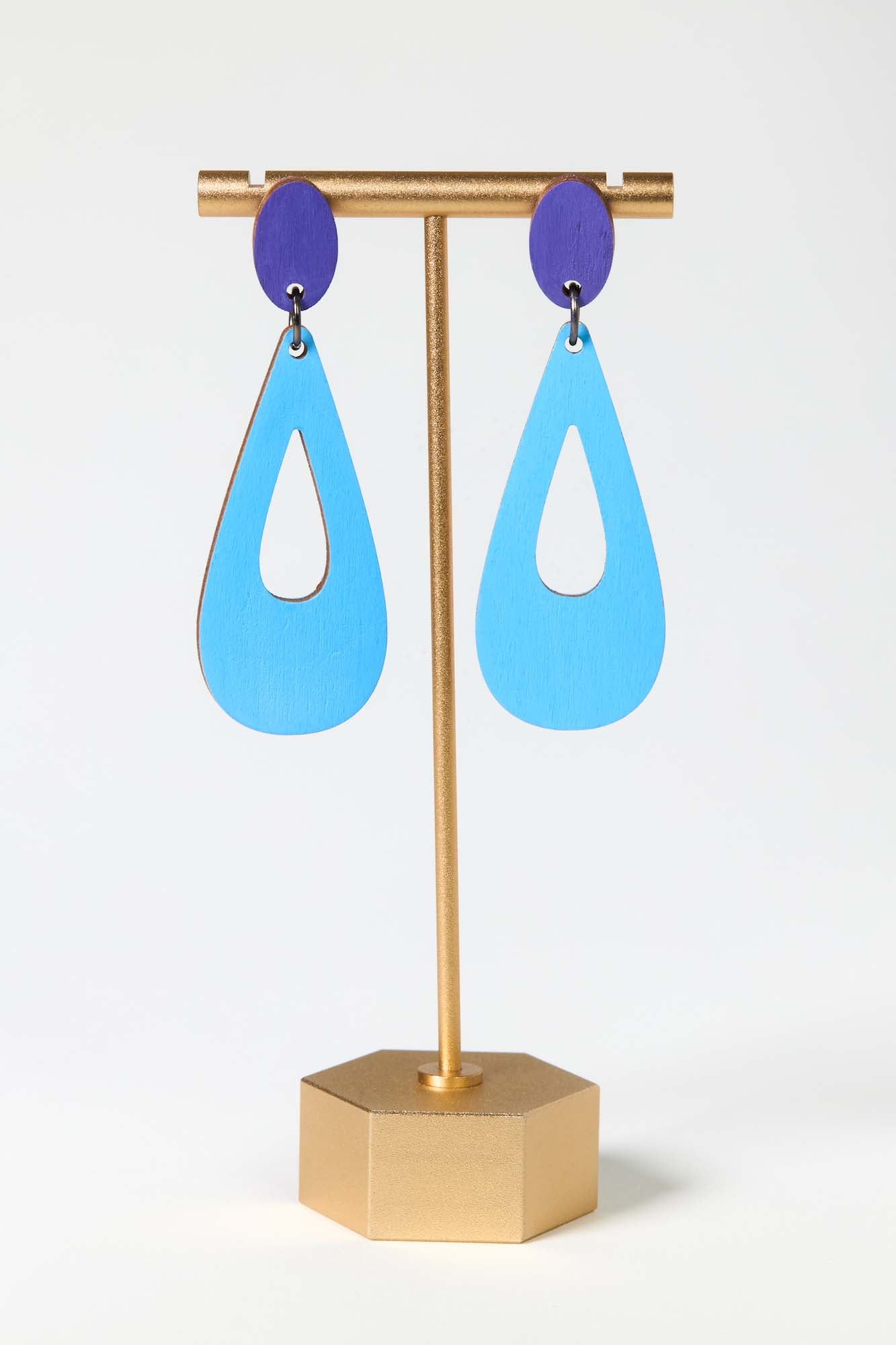Blue earrings on a gold stand against a white background