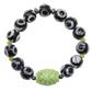 Black and white beaded bracelet with a green carved bead on a white background