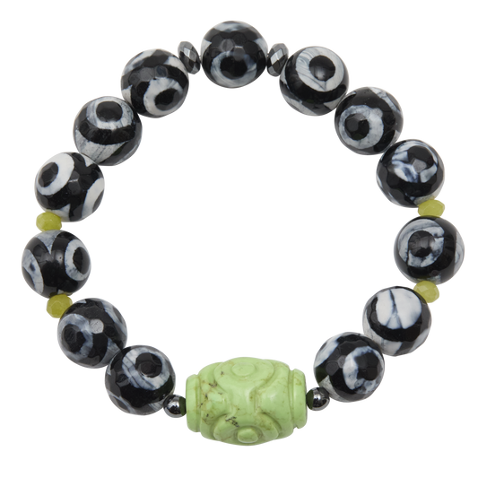 Black and white beaded bracelet with a green carved bead on a white background
