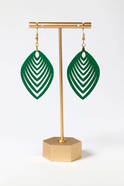 Green leaf-shaped earrings on a gold stand against a white background