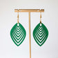 Green leaf-shaped earrings on a gold earring stand against a white background