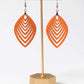Orange earrings on a gold earring stand against a white background