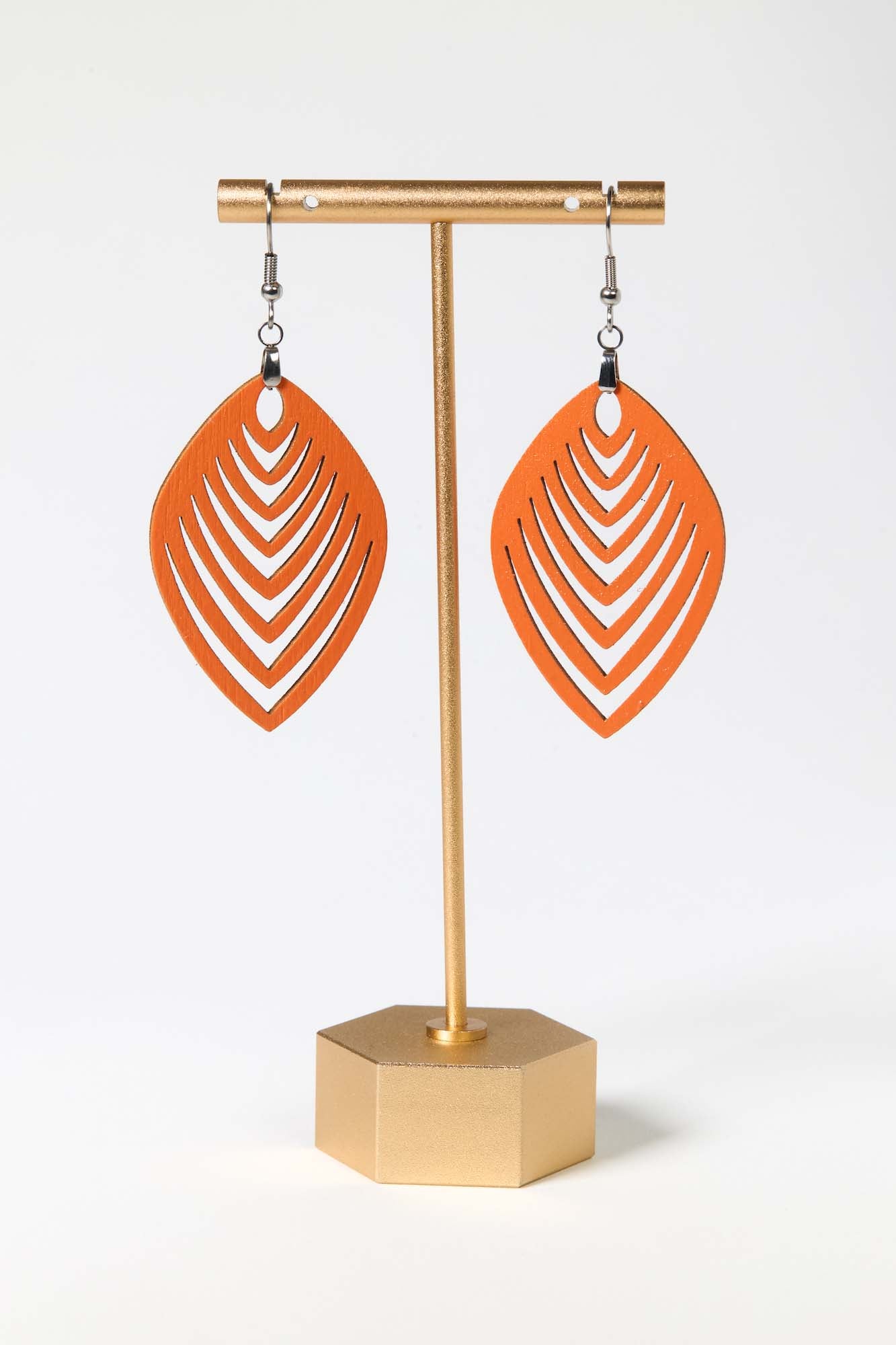 Orange earrings on a gold earring stand against a white background