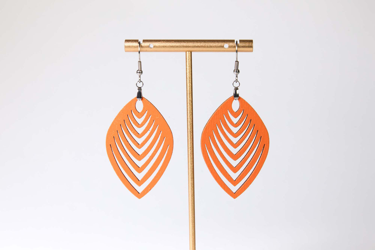Orange earrings on a gold earring stand against a white background