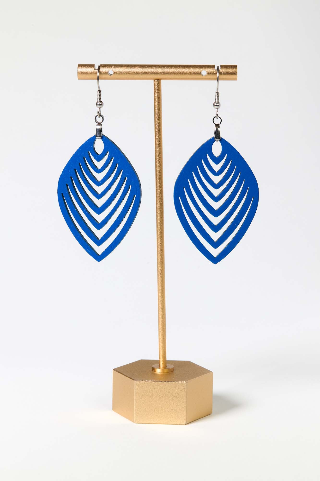 Blue earrings on a gold stand against a white background