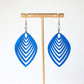 Blue leaf-shaped earrings on a gold earring stand against a white background