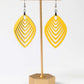 Yellow earrings on a gold earring stand against a white background
