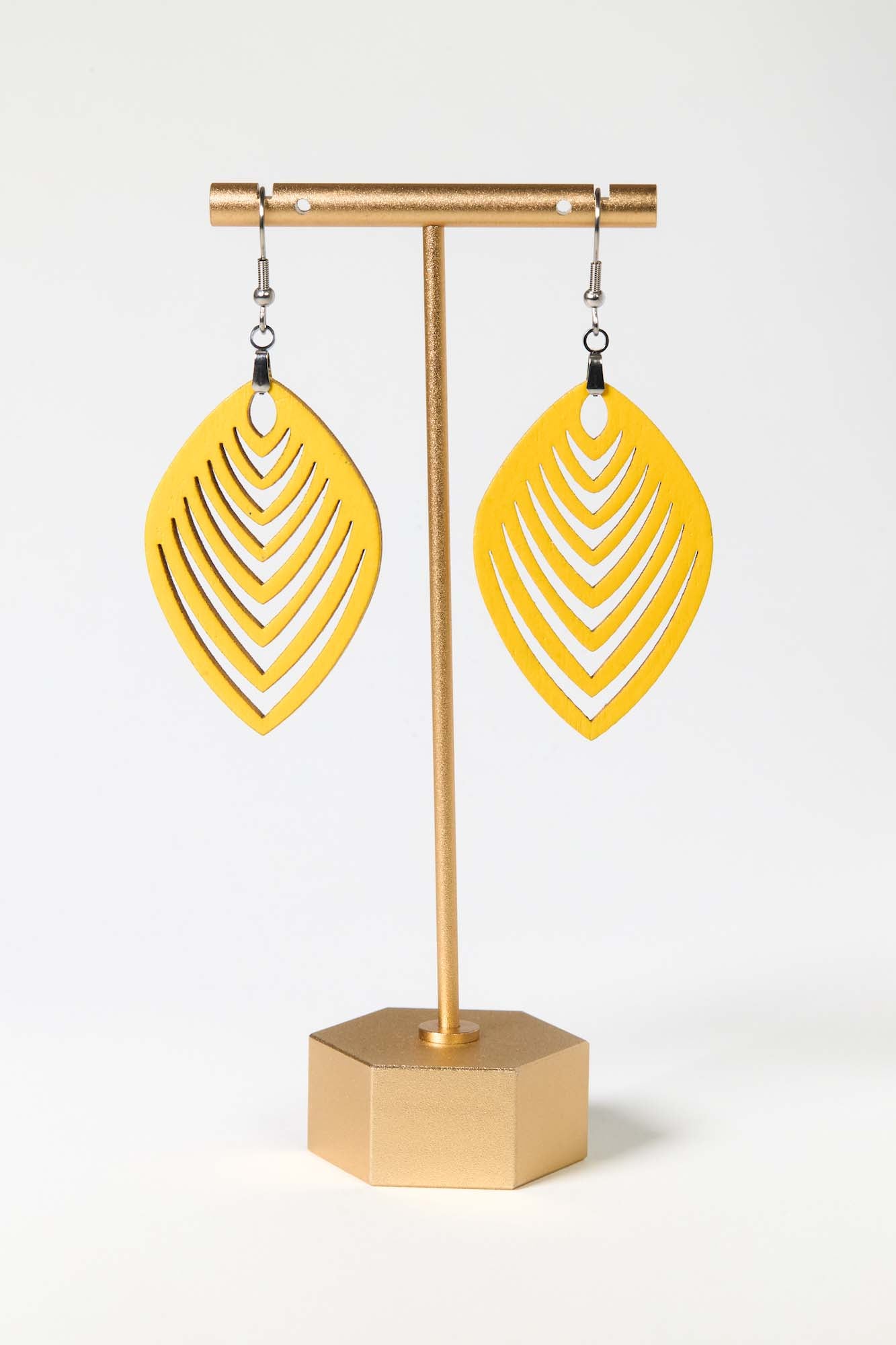 Yellow earrings on a gold earring stand against a white background