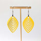 Yellow earrings on a gold earring stand against a white background