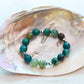 Beaded bracelet with green and brown stones on a shell