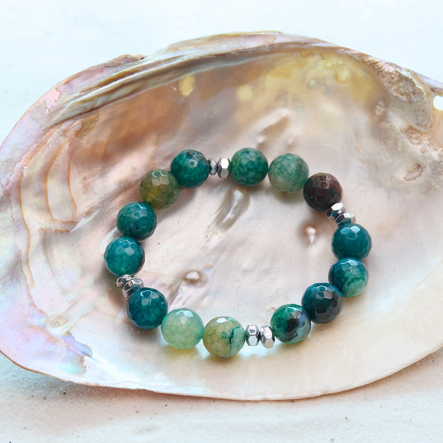 Beaded bracelet with green and brown stones on a shell