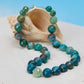 Necklace with blue and green beads on a shell against a blue background